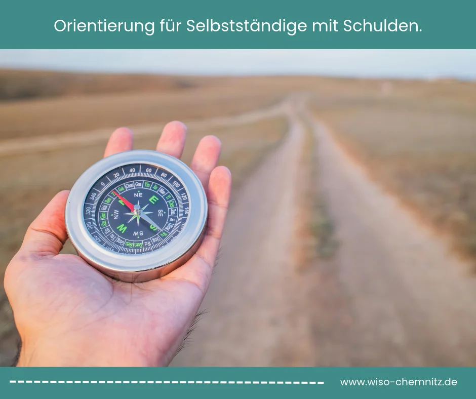 Hand hält einen Kompass vor einem Feldweg. Symbolbild für Selbstständige mit Schulden auf der Suche nach der zuständigen Anlaufstelle in Chemnitz.